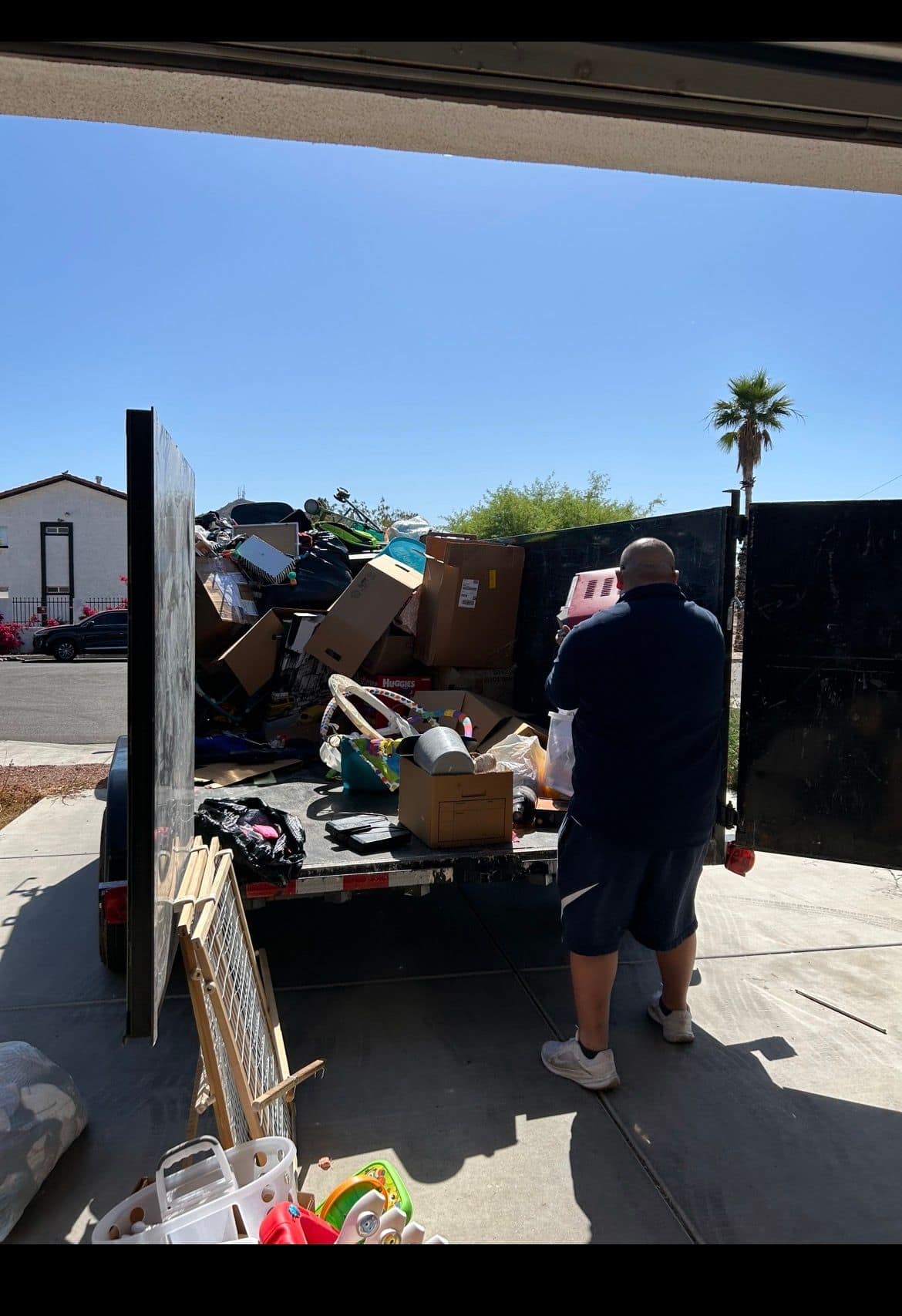 AZ Junk Pros crew member loading household clutter from a garage cleanout into the dump trailer